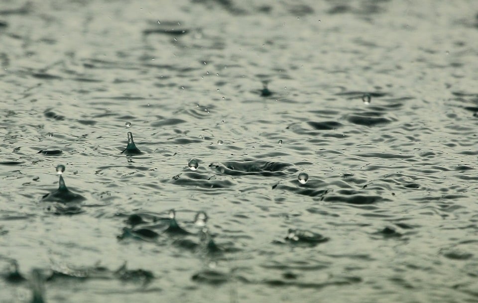 Close em gotas de chuva caindo em poça