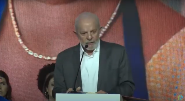 Presidente Lula em discurso usando blazer cinza e camisa branca