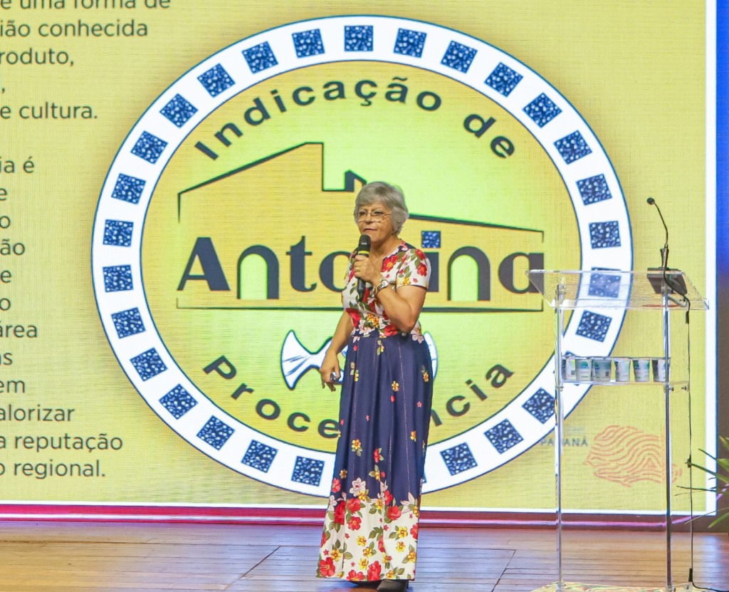 Mulher no palco com microfone na mão 