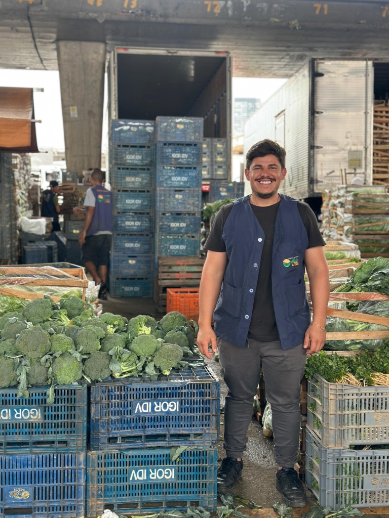 Homem em pé com o fundo de caixas de verduras, na Ceagesp