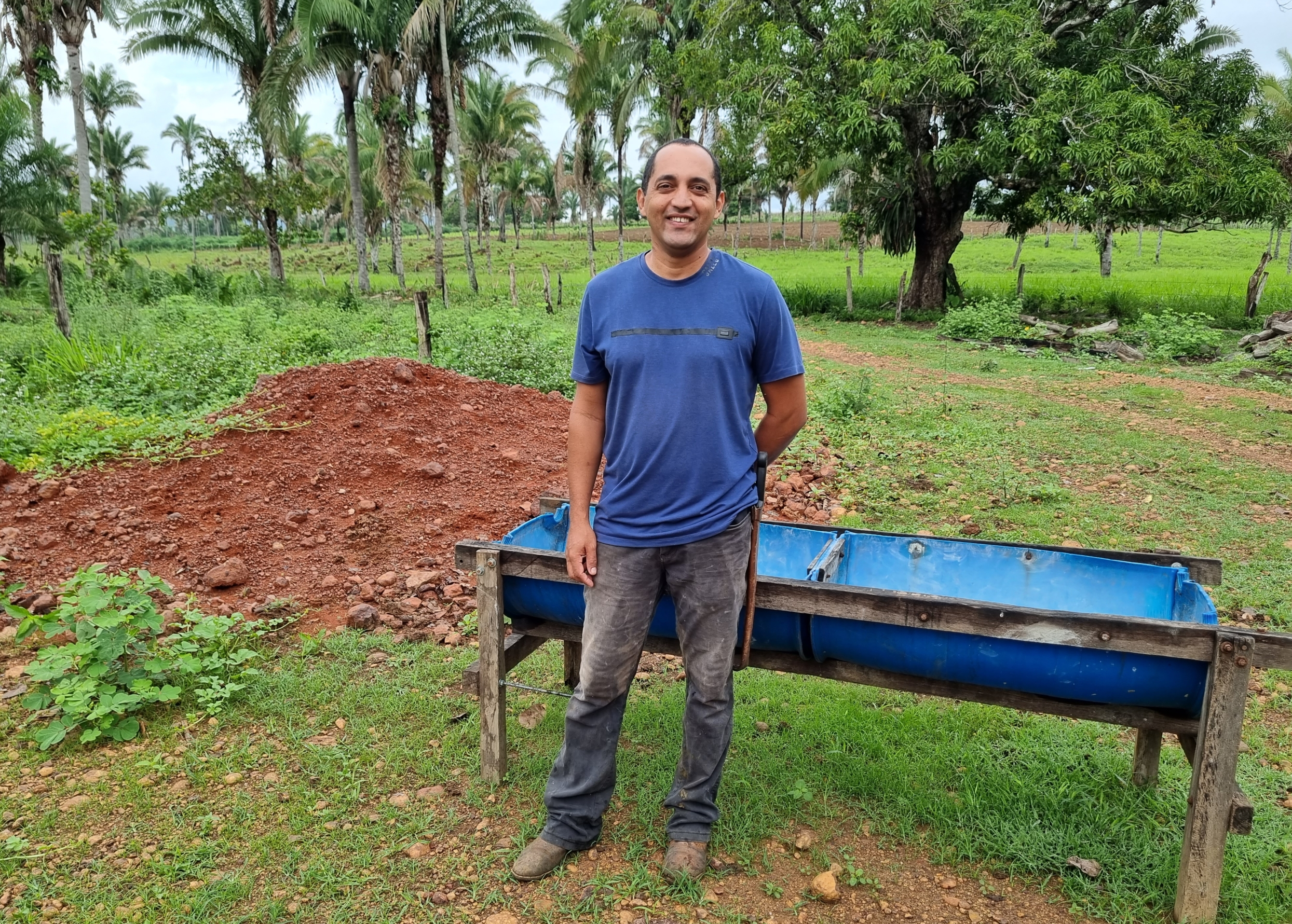 Um homem em pé com o fundo de sua fazenda