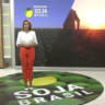 Apresentadora com camisa branca e calça laranja no estúdio do Soja Brasil