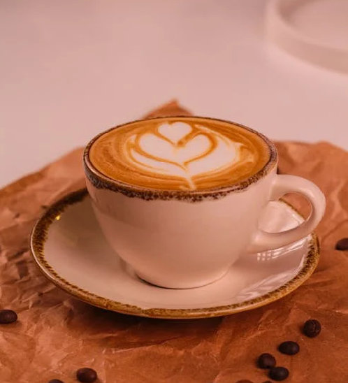 Uma xícara de café com grãos espalhados por um mesa