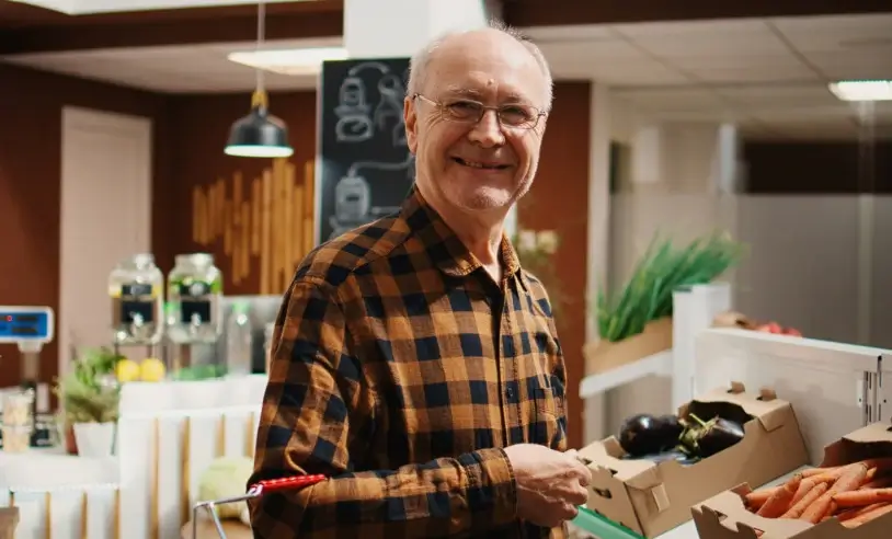 Homem de cabelos grisalhos sorrindo em um hortifruti