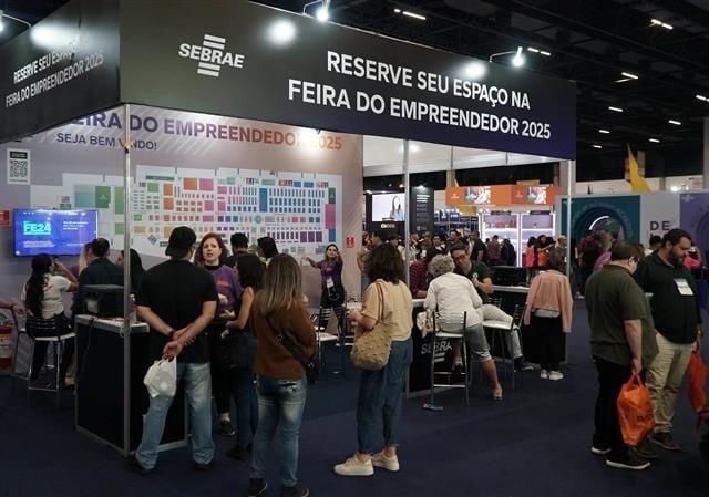 a foto mostra um estande do ano de 2024 com pessoas reunidas em volta do mesmo