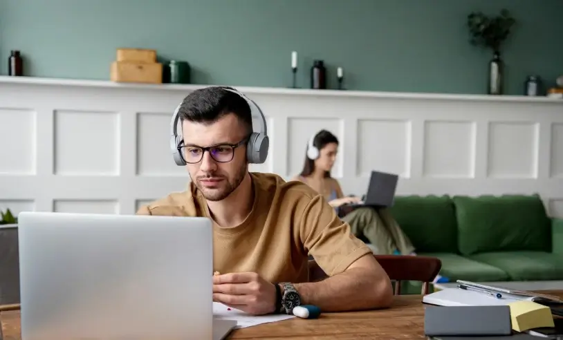 Homem com fone de ouvido e com notebook à sua frente
