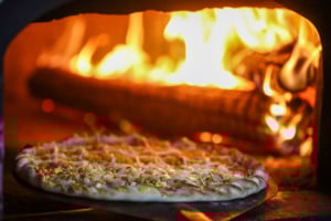Em um forno à lenha, há um pizza sendo preparada