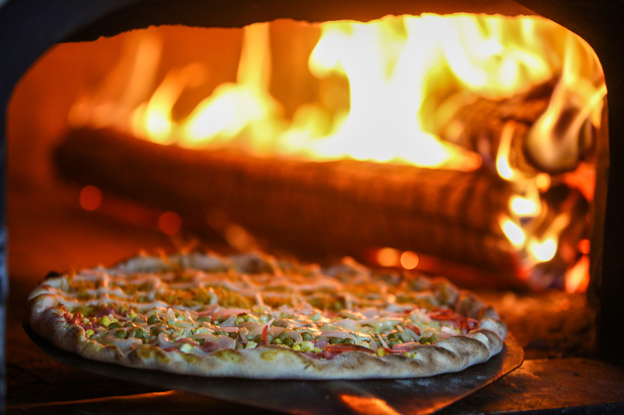 Em um forno à lenha, há um pizza sendo preparada