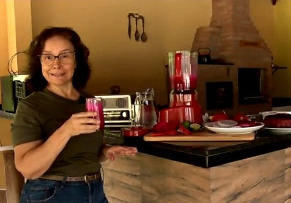 Mulher segurando um copo e dentro há suco de pitaia