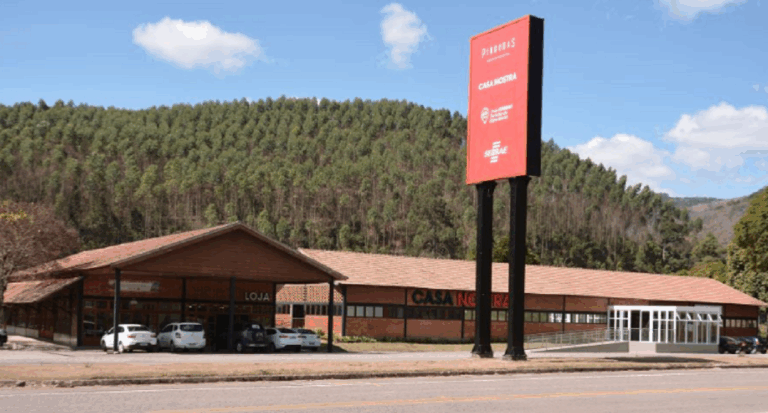 Na foto, há duas casa, sendo uma do Sebrae e outra uma loja. À frente há uma placa indicando o distrito de Pindobas, em Venda Nova do Imigrante no Espírito Santo.