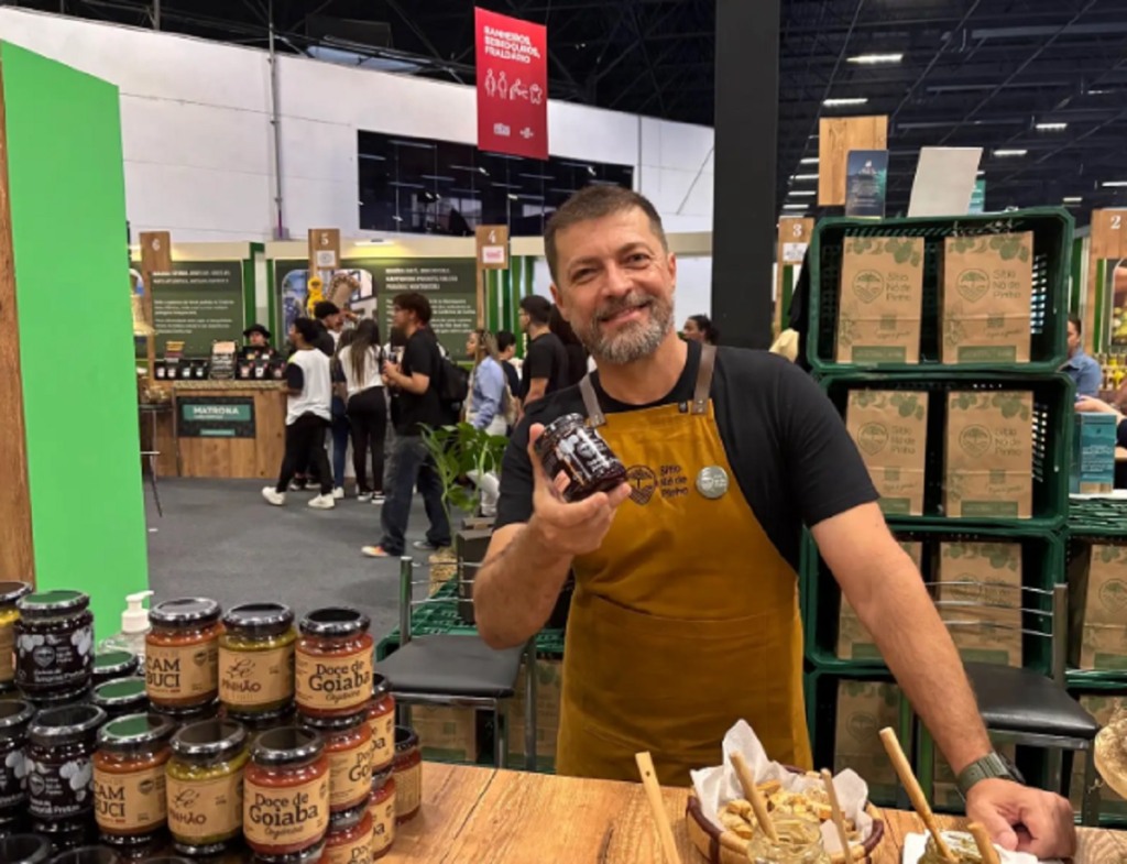 Homem com um pote de geleia na mão direita. Ele participa da Feira do Empreendedor em São Paulo