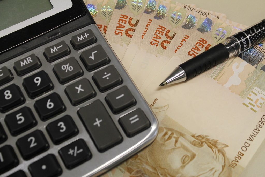 Calculadora e caneta preta sobre notas de 50 reais