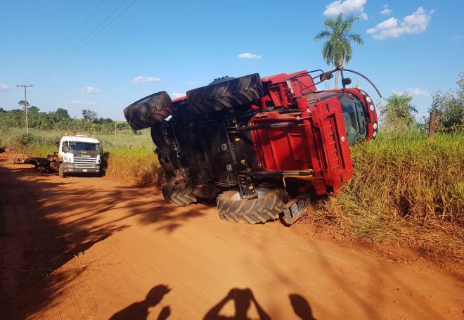 Transportador tenta desvio por estrada de terra e derruba colheitadeira