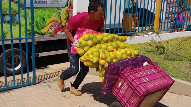 Homem carrega alimentos em cima de carrinho durante entrega em creche de São Desidério (BA)