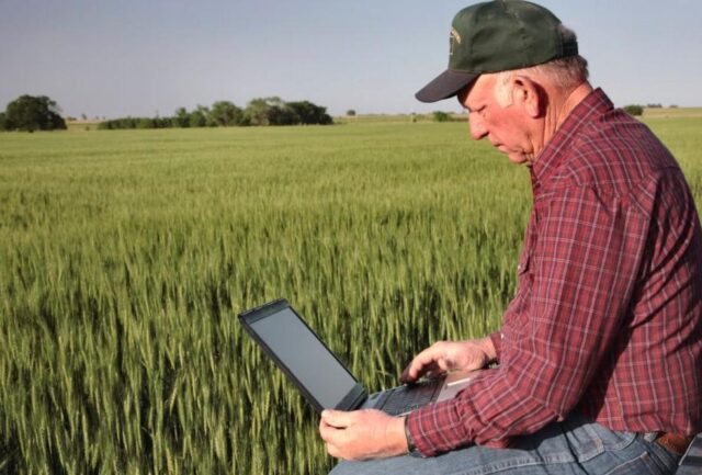 Home idoso no campo com um computador no colo acessando a internet 5G