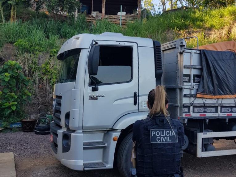 Policial civil na frente de caminhão usado para transportar cargas de grãos furtadas