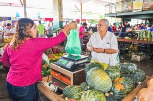 Produtora da Ceasa entregando verdura para comprador