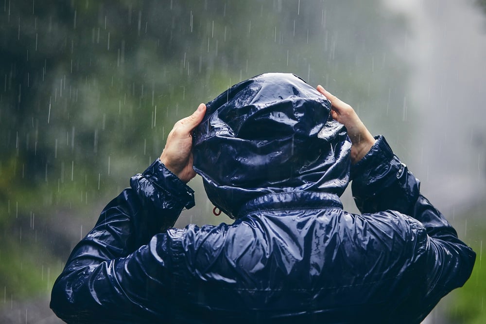 homem com capuz em chuva forte